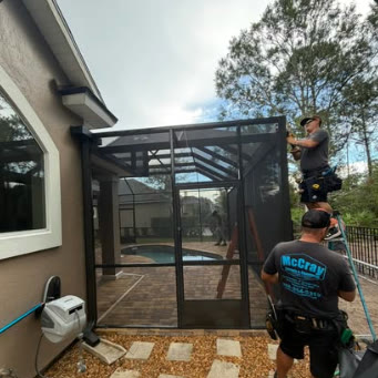 McCray crew member installing the frame of a new screen enclosure beside a pool
