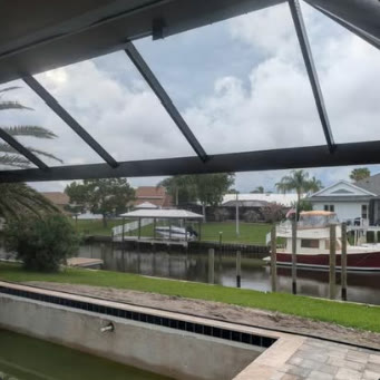 Screen enclosure framing a canal and boat dock behind a waterfront home