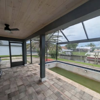Covered lanai with ceiling fan opening onto a screened pool deck on the water