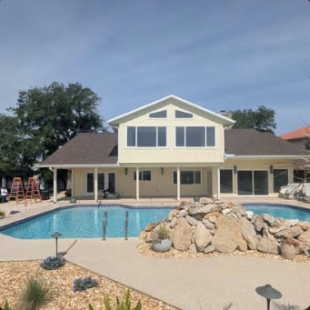 Two-storey home with a screened lanai and pool deck, seen across the yard