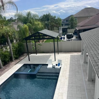 Freestanding dark aluminium cover beside a rectangular pool and paver deck