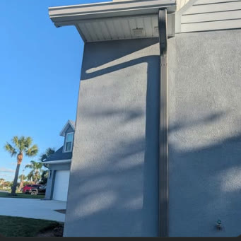 Seamless gutter and downspout run on the corner of a stucco house